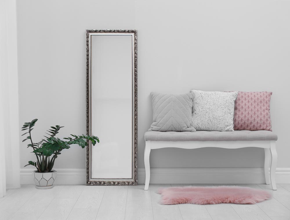 Modern large mirror and comfortable bench near light wall in roo
